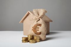 stack of gold coins and the figure of crafting house bag with money and euro sign investment in estate property home rental 153566794
